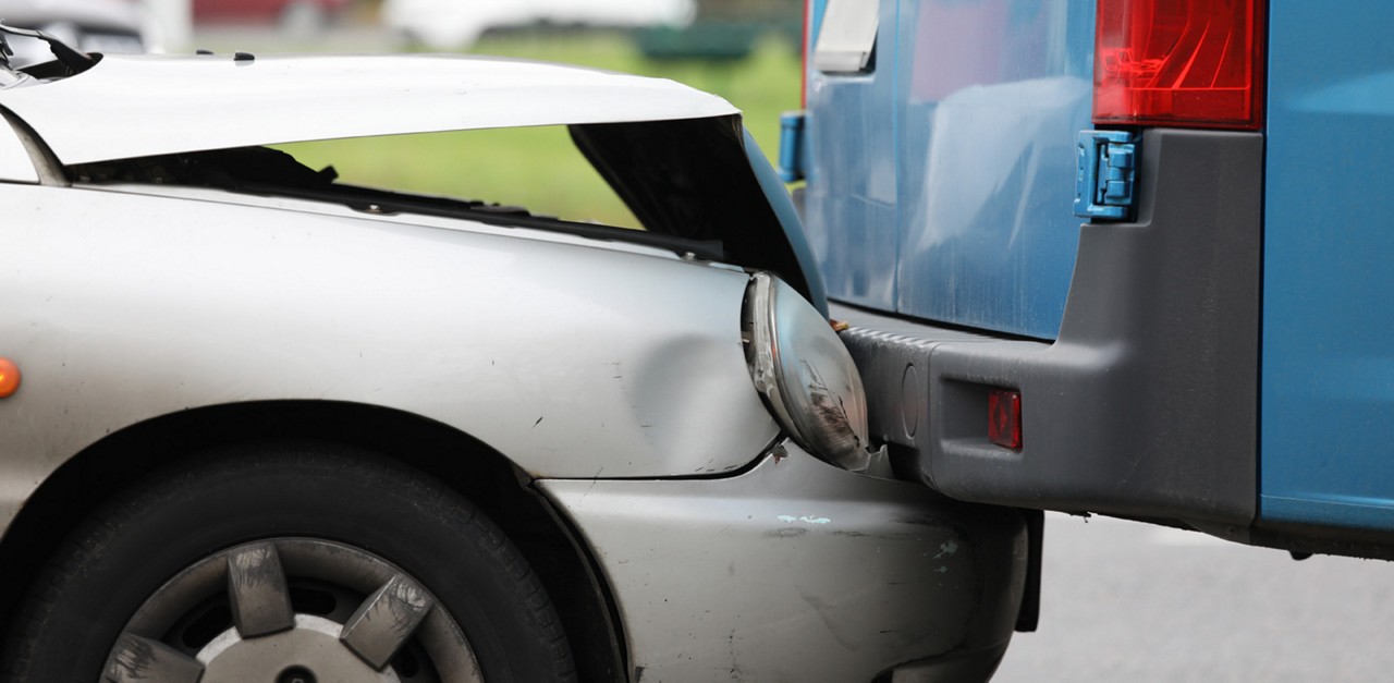 Close-up view of grey car crashed into blue truck. Auto accident on city street. Dangerous situation for vehicle. Traffic trouble and insurance claim concept