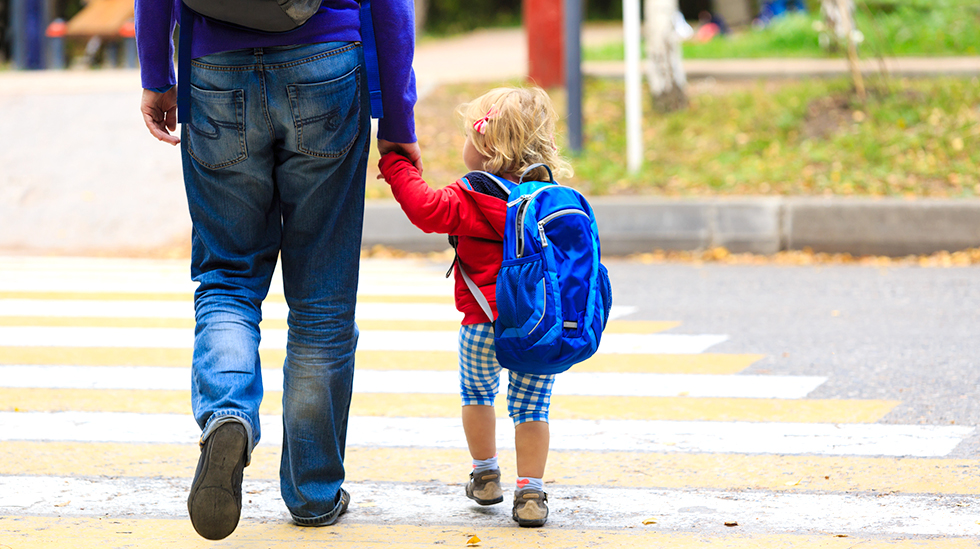 father walking little daughter with backpack to school or daycare